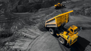 A top aerial view of an open pit mine industry, with a big yellow mining truck for coal